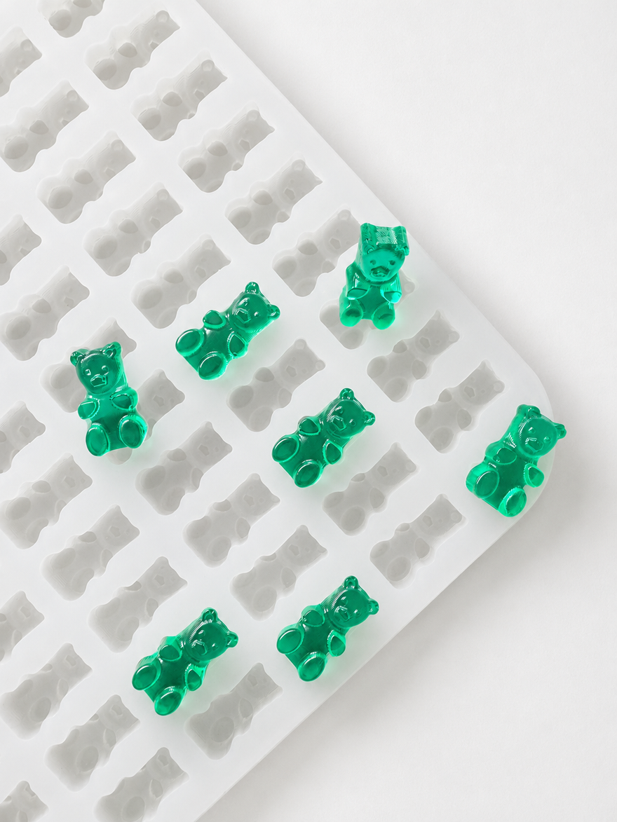 Commercial gummy bear mold with finished translucent emerald green gummy bears